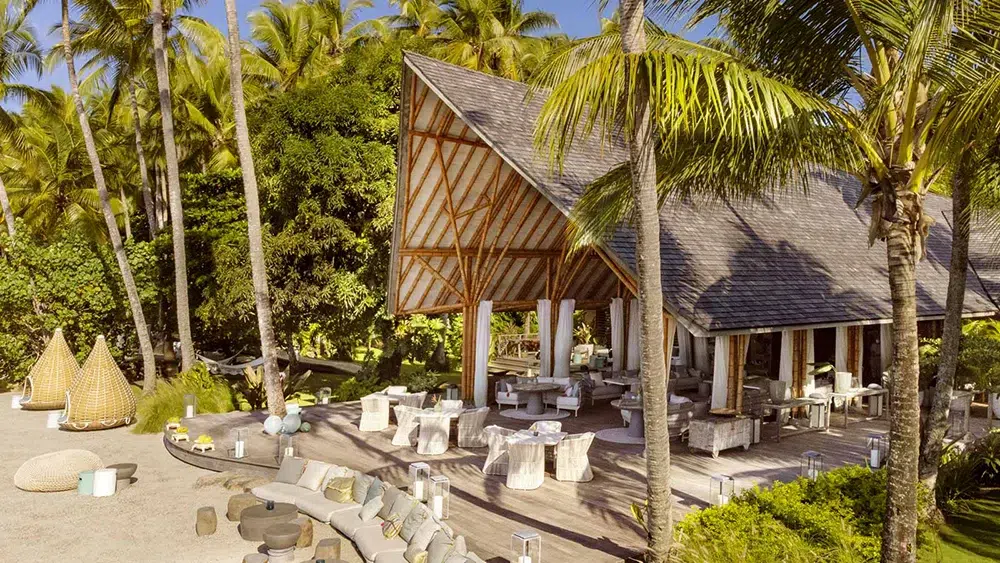 Tranquil beachfront lounge at Islas Secas with woven cabanas and candlelit ambiance amid lush greenery.