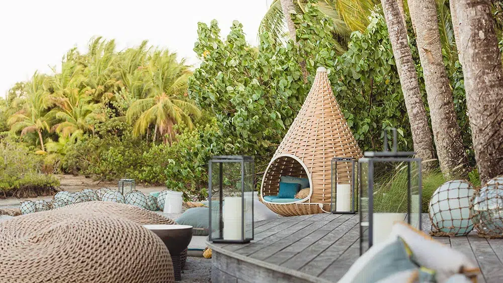 Tranquil beachfront lounge at Islas Secas with woven cabanas and candlelit ambiance amid lush greenery.