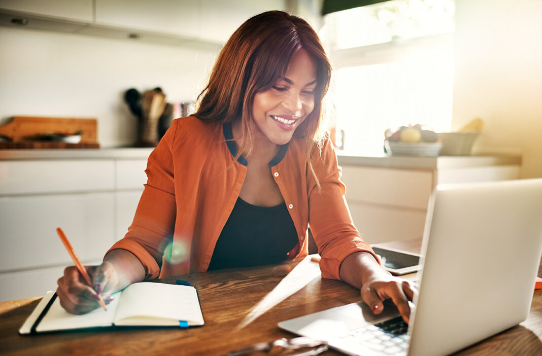 Smiling young female entrepreneur working at her kitchen table