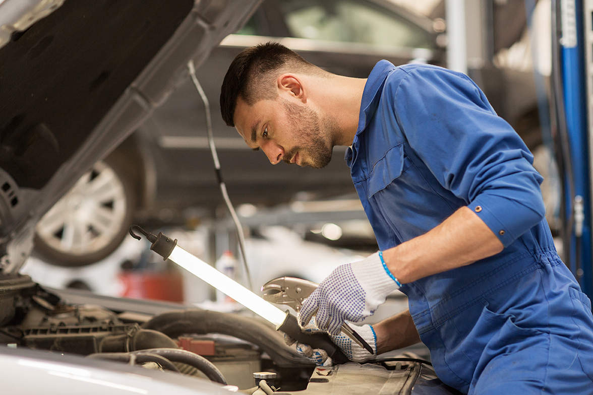 mechanic man with lamp repairing car at workshop mechanic man with lamp repairing car at workshop