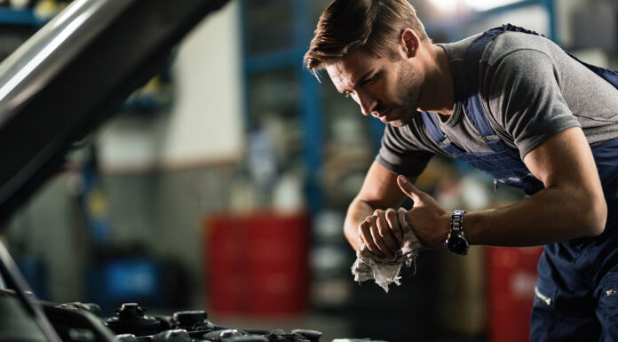 A Simple Guide To Being A Good Mechanic Young auto mechanic cleaning hands after working on car engine in a garage.
