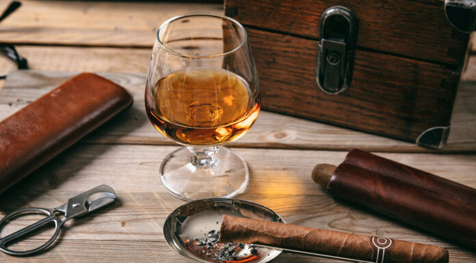 Our Cigar Picks This Season from a Global Collection of Rollers Cuban cigar and a glass of cognac brandy on wooden background