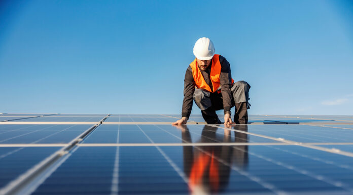 5 Effects Of Installing Solar Panels On Your Insurance A handyman installing solar panels on the rooftop.