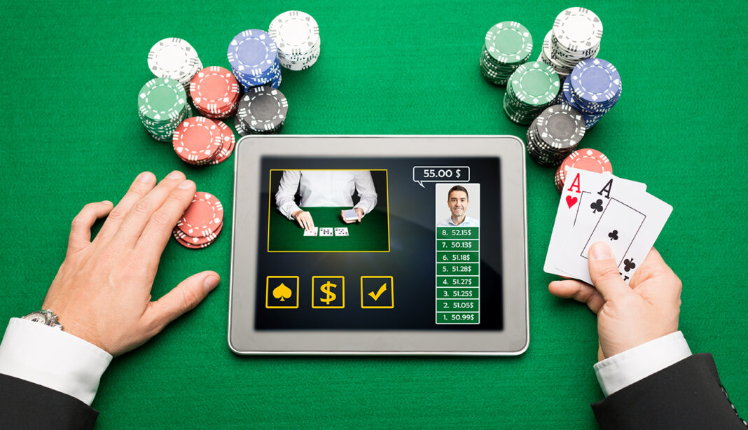 casino, online gambling, technology and people concept - close up of poker player hands with playing cards, tablet pc computer and chips at green casino table