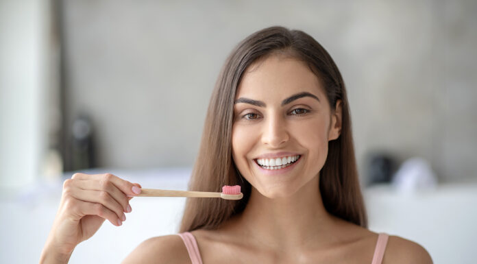 How a Healthy Smile Embodies and Amplifies Inner Beauty Smiling woman brushing her teeth with a bamboo toothbrush showing a healthy smile