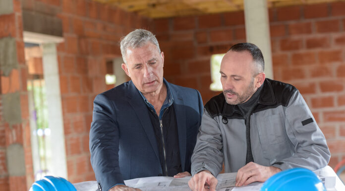 4 Essential Considerations When Hiring a Contractor for Your New Home Construction Architect and contractor looking at plans on a building site