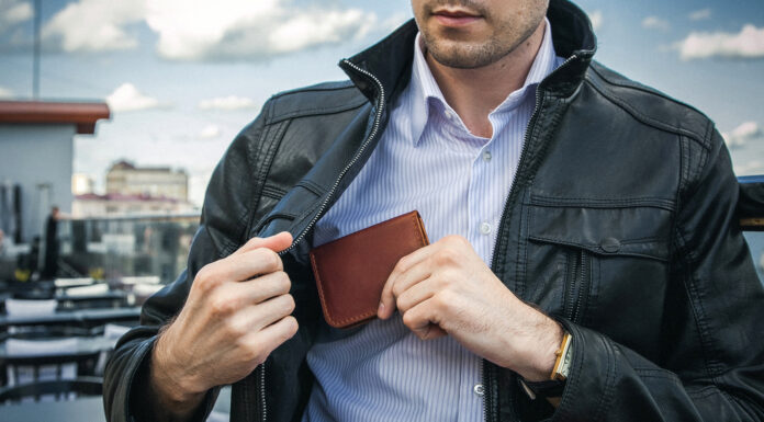 Why Investing In A Luxury Leather Wallet Is Worth The Money A man in a black leather jacket pulls out a wallet from an inside pocket. Photo via adobestock