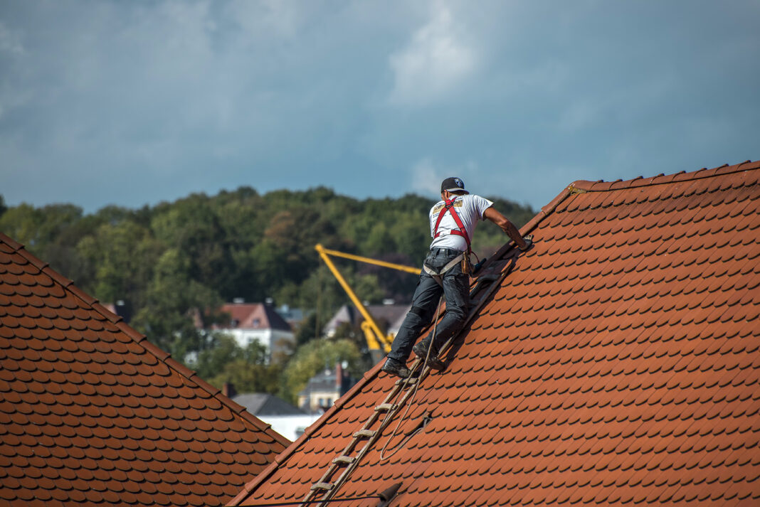 Roofer on top the roof of a house. Photo via pixabay