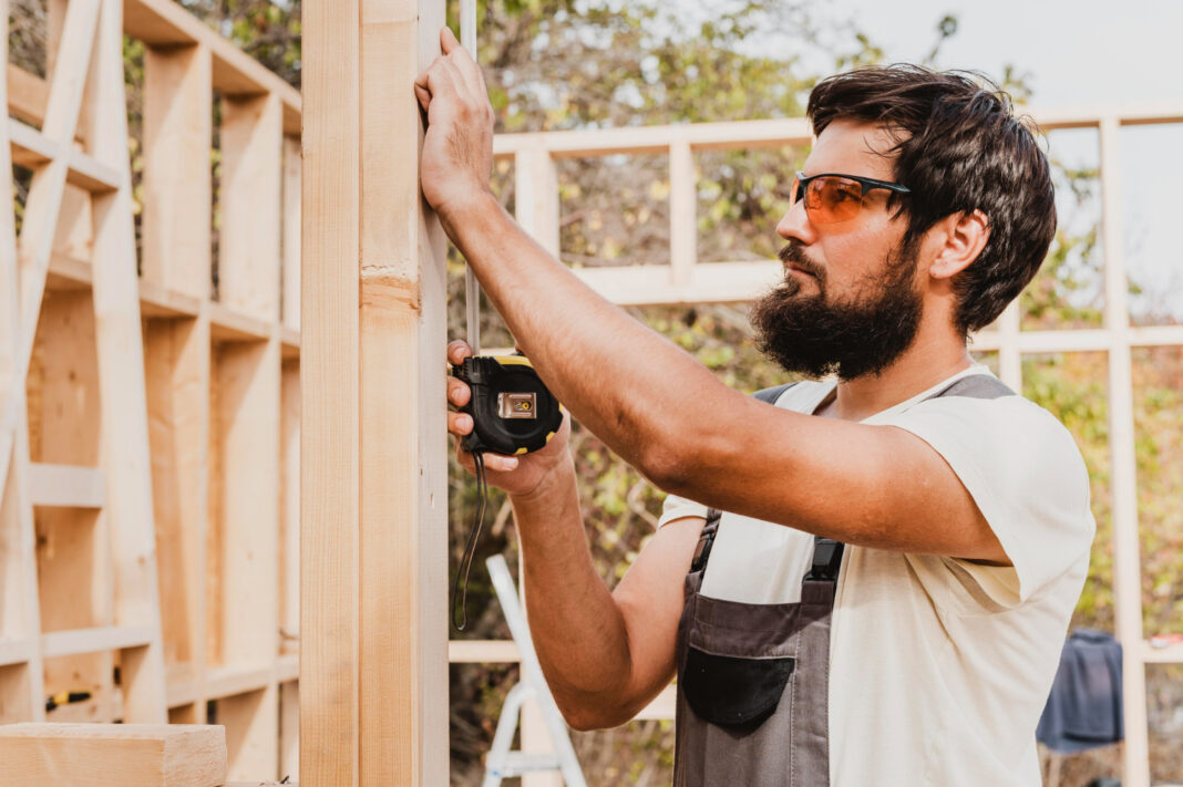 carpenter man using a tape measure. Photo by Freepik
