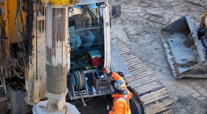 What to Do if You’re Injured at Work men standing next to heavy equipment at work. Photo by IslandHopper X via pexel