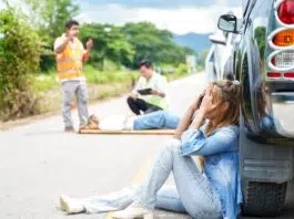 a young woman sits crying next to the car she crashed causing an accident