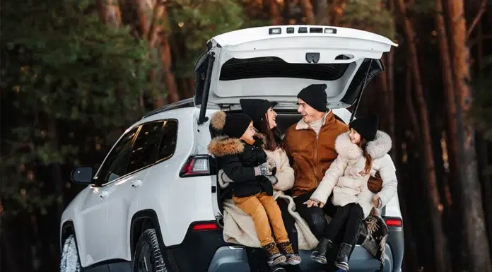 Road Trip Tire Checklist: What You Need Before You Hit the Road Family enjoying a winter getaway, sitting in the open trunk of a luxury SUV surrounded by snow-covered woods.