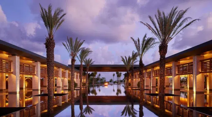 Conrad Tulum Resort: A New Standard of Luxury Elegant resort entrance with palm-lined reflective water feature framed by modern architecture at dusk.