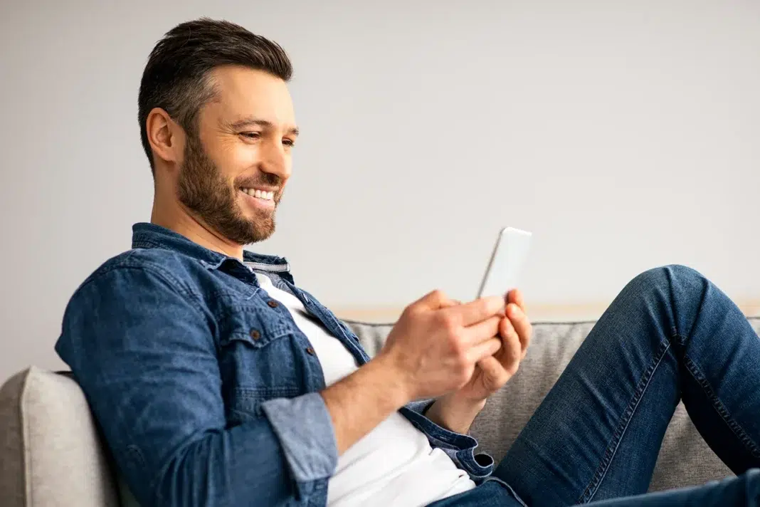 Man happily playing a game while relaxing on his couch. Photo via vecteezy Man happily playing a game while relaxing on his couch. Photo via vecteezy