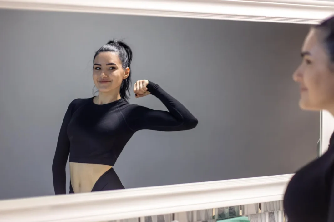 Beautiful woman in sportswear looking at mirror Beautiful woman in sportswear looking at mirror