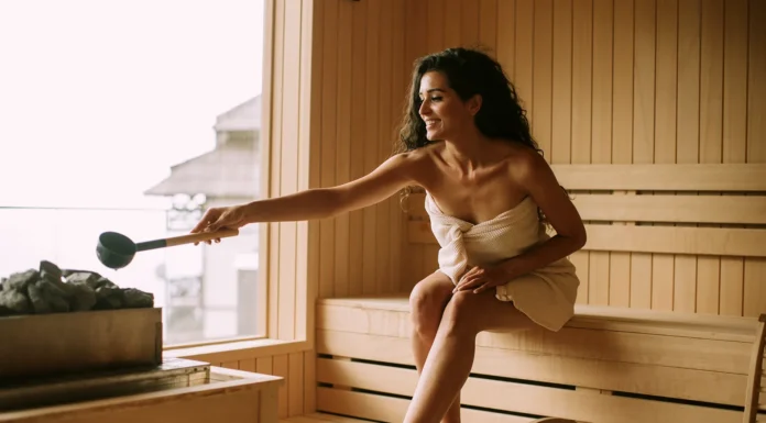 The Health Benefits of Installing a Home Sauna A young woman pouring water onto hot stone in her home sauna. Vecteezy-medium