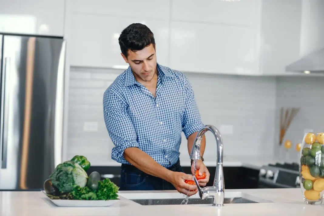 Men in his kitchen trying to lower his water bill. Photo by magnific Men in his kitchen trying to lower his water bill. Photo by magnific
