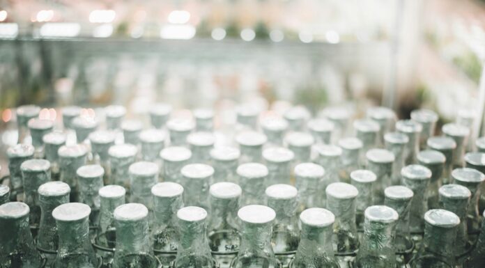 How Premium Supplement Brands Are Really Made Rows of glass supplement bottles on a clean white production line. Photo by Chuttersnap via unsplash