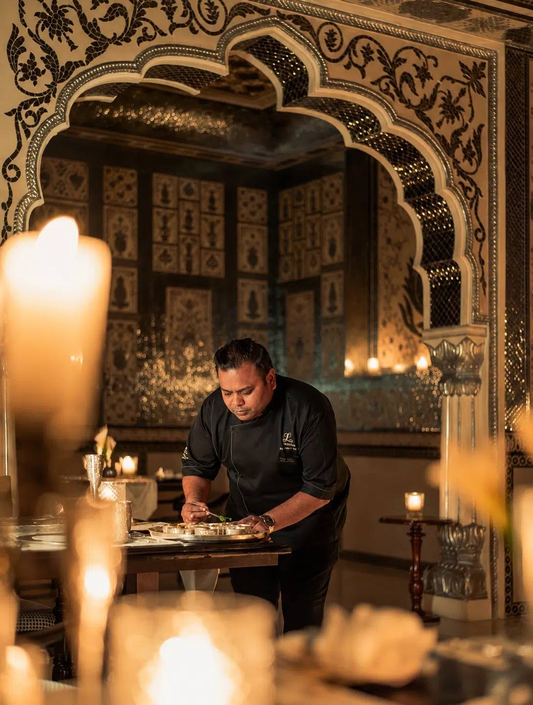 A member of Jamavar Jaipur’s culinary team works beneath the restaurant’s ornate arches, where craftsmanship extends from the dining room to the plate. A member of Jamavar Jaipur’s culinary team works beneath the restaurant’s ornate arches, where craftsmanship extends from the dining room to the plate.