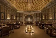Inside Jaipur’s Candlelit Palace of Mirrors A wide view of Jamavar Jaipur’s no-electricity dining room reveals the dramatic interplay of candlelight, handcrafted surfaces and regal symmetry.