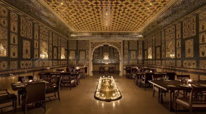 Inside Jaipur’s Candlelit Palace of Mirrors A wide view of Jamavar Jaipur’s no-electricity dining room reveals the dramatic interplay of candlelight, handcrafted surfaces and regal symmetry.