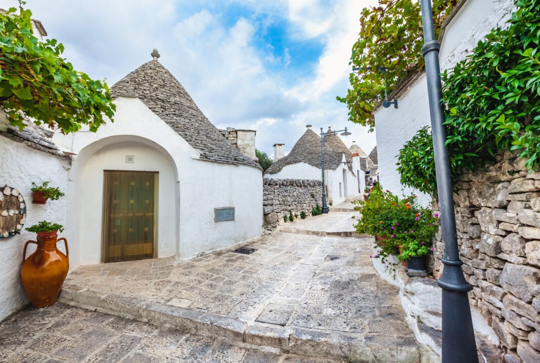 Beautiful town of Alberobello with Trulli houses among green plants and flowers, Apulia region, Southern Italy. Puglia, Italy