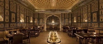 A wide view of Jamavar Jaipur’s no-electricity dining room reveals the dramatic interplay of candlelight, handcrafted surfaces and regal symmetry.